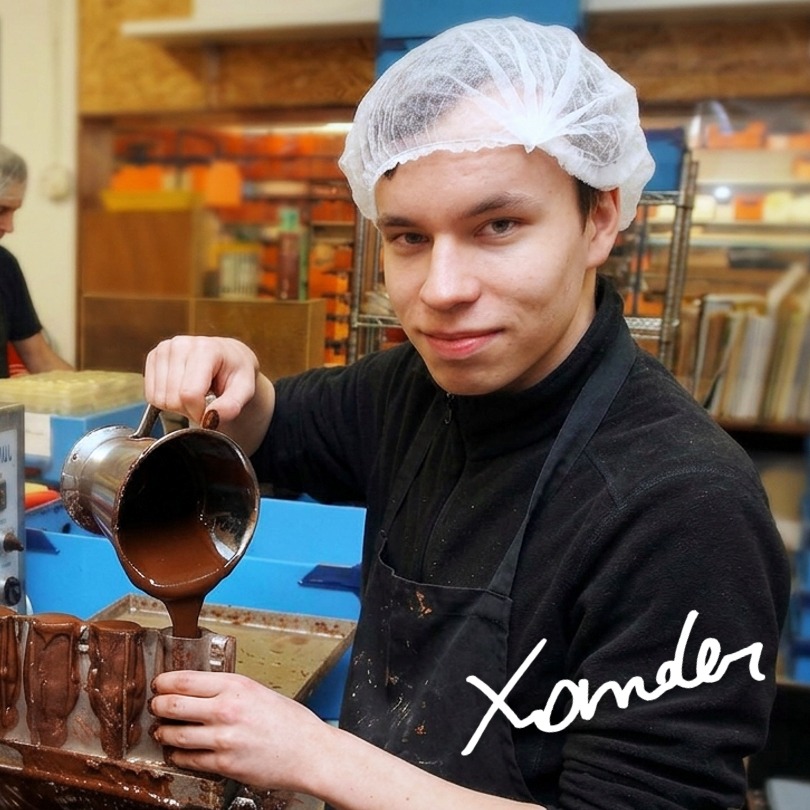 Persoon met haarnet schenkt chocolade in een vorm in een keukenomgeving.